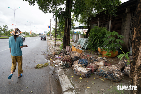 10 năm liền 'đá nhau' duy tu 13km vỉa hè, dải cây xanh quốc lộ 1A - Ảnh 1. Vỉa hè quốc lộ 1A đoạn qua xã Triệu Ái (huyện Triệu Phong) chất đầy bao xi măng, rác thải nên người đi bộ phải đi xuống lòng đường - Ảnh: HOÀNG TÁO