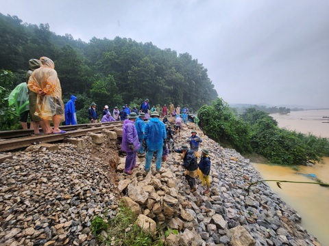 Thông đường sắt Bắc - Nam qua Hà Tĩnh sau gần 2 ngày ách tắc - Ảnh 3. Vị trí sạt lở nằm cạnh bờ sông Ngàn Sâu nên công nhân đường sắt chuyền tay từng viên đá để đắp lại nền đường - Ảnh: VNR