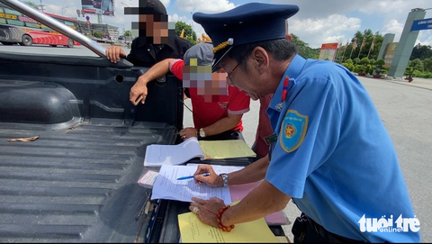 CSGT TP.HCM phạt tài xế xe khách bằng lái đang bị tạm giữ vẫn chạy xe - Ảnh 1. Tài xế P. (áo đỏ) bị thanh tra giao thông lập biên bản vi phạm - Ảnh: KHẮC HIẾU