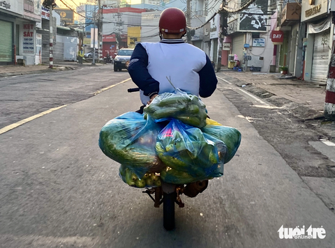 - Ảnh 3. Chiếc xe thồ rau củ với nhiều bao bì móc sau xe trên đường Võ Văn Ngân