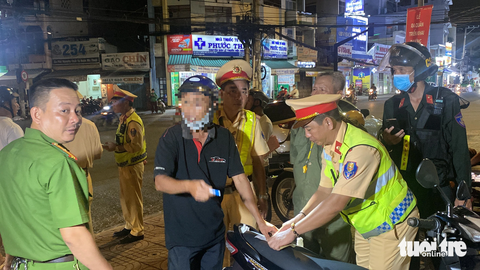 Người đàn ông rút ống xăng, cầm bật lửa, khi bị cảnh sát kiểm tra nồng độ cồn - Ảnh 1. Cảnh sát đã lập biên bản người đàn ông rút ống bình xăng, cầm bật lửa dọa đốt xe - có nồng độ cồn 0,689mg/l - Ảnh: HOÀI THƯƠNG