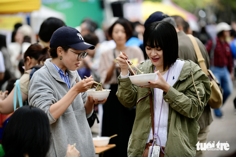 Thực khách thưởng thức phở tại công viên Yoyogi, Tokyo, Nhật Bản sáng 8-10 - Ảnh: QUANG ĐỊNH Với người Nhật Bản, đứng ăn các món sợi là cách ăn phổ biến.