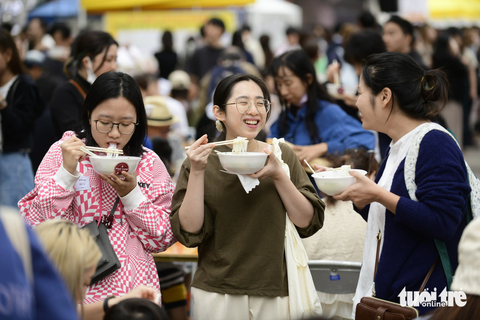 Thực khách thưởng thức phở tại công viên Yoyogi, Tokyo, Nhật Bản sáng 8-10 - Ảnh: QUANG ĐỊNH Hà Phương, Hồng Linh, Thu Trà mới qua Nhật Bản được ba tháng. Họ cho hay cực kỳ thèm phở và chọn phở Thìn Bờ Hồ
