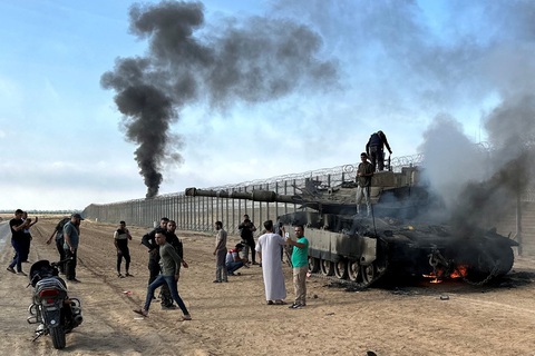 Người Palestine chụp ảnh cùng xe tăng bốc cháy của Israel, sau khi chiếc xe bị các tay súng Hamas xâm nhập từ phía Nam tấn công, tại khu vực gần biên giới Israel - Gaza, ngày 7-10 - Ảnh: REUTERS Người Palestine chụp ảnh bên cạnh chiếc xe tăng bốc cháy của Israel, sau khi chiếc xe bị các tay súng Hamas tấn công tại khu vực gần biên giới Israel - Gaza, ngày 7-10 - Ảnh: REUTERS
