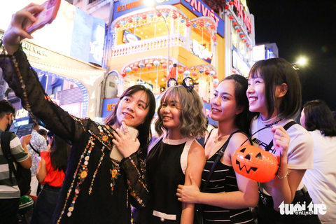 Đêm Halloween: người dân đổ về trung tâm TP.HCM với muôn kiểu hóa trang - Ảnh 4. Nhóm bạn của Thảo Ngân (bìa phải) hào hứng "tự sướng" với chiếc túi bí ngô vừa tậu để quẩy cùng mọi người