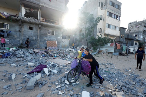 Dải Gaza cận kề thảm họa nhân đạo - Ảnh 1. Các em trai người Palestine phía trước dãy nhà bị phá hủy trong đợt không kích của Israel tại vùng Khan Younis ở phía nam Dải Gaza hôm 30-10 - Ảnh: REUTERS