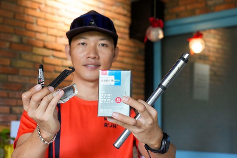 'Để đạp xe vui khỏe, không phải cứ nhảy lên xe là được !' - Ảnh 3. Anh Phúc bên bộ dụng cụ cơ bản cho việc đi xe đạp. Cụ thể, tay trái là bộ vá ruột xe (gồm keo vá, bộ nạy và miếng vá). Tay phải là hộp đựng ruột bánh xe dự phòng và bơm xe đạp