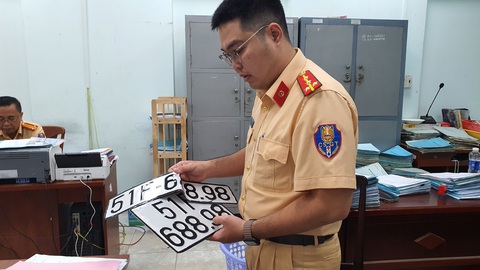 Cục bất ngờ đổi quy định, dân chơi biển số đẹp nói bị ‘sụp hầm’ - Ảnh 2. Cán bộ cảnh sát giao thông ở TP.HCM thu hồi biển số định danh - Ảnh: MINH HÒA