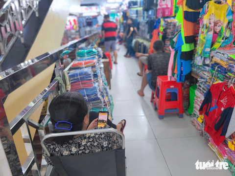 Chợ vắng khách, tiểu thương nghĩ ra đủ kiểu 'giết thời gian' - Ảnh 3. Âm thanh chủ đạo tại các chợ sỉ không còn là tiếng sột soạt gói hàng, tiếng trao đổi trả giá mà là âm thanh phát ra từ những chiếc smart phone - ẢNH: NHẬT XUÂN