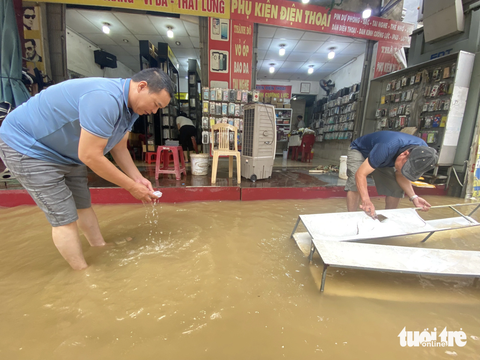 Người dân Huế tất bật dọn dẹp nhà cửa, trụ sở, đường sá sau khi nước lũ rút- Ảnh 3. Nước lũ rút ra, người dân dọn dẹp vệ sinh cửa hàng - Ảnh: LÊ TRUNG