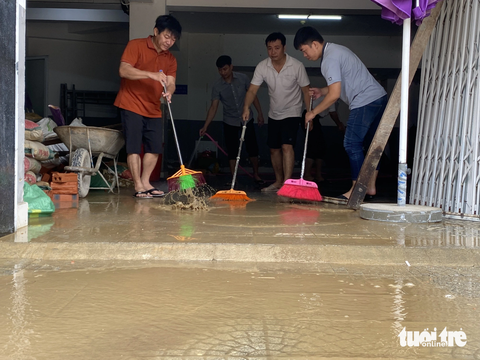 Người dân Huế tất bật dọn dẹp nhà cửa, trụ sở, đường sá sau khi nước lũ rút- Ảnh 5. Nhân viên một ngân hàng dọn bùn non sau lũ - Ảnh: LÊ TRUNG