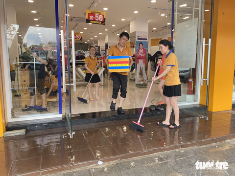 Người dân Huế tất bật dọn dẹp nhà cửa, trụ sở, đường sá sau khi nước lũ rút- Ảnh 8. Nhân viên cửa hàng quần áo dọn vệ sinh sau lũ - Ảnh: LÊ TRUNG