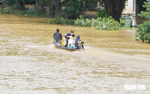 Trời nắng, nhiều tuyến phố ở Huế vẫn còn chìm trong nước lũ - Ảnh 4. Người và xe về nhà bằng ghe - Ảnh: LÊ TRUNG