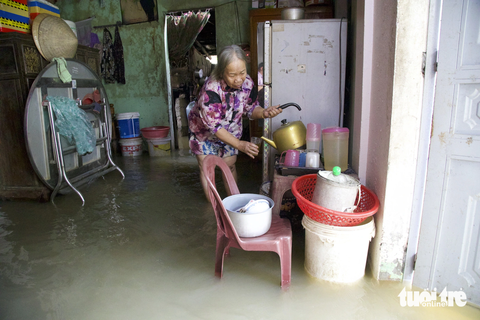 Xóm giềng cứu giúp nhau trong lũ dữ - Ảnh 1. Bà Nguyễn Thị Gái trở về dọn dẹp nhà sau một đêm tránh lũ ở nhà hàng xóm - Ảnh: HOÀNG TÁO