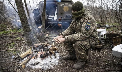 Một người lính Ukraine cố gắng giữ ấm trên tiền tuyến ở tỉnh Donetsk. Ảnh: ANADOLU AGENCY Một người lính Ukraine cố gắng giữ ấm trên tiền tuyến ở tỉnh Donetsk - Ảnh: ANADOLU AGENCY