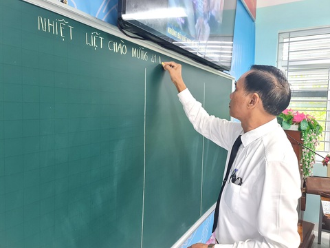 Người thầy hạnh phúc và tiết dạy cuối cùng- Ảnh 2. Thầy Tuệ đến trường sớm, chuẩn bị cho tiết dạy và viết dòng chữ chào mừng Ngày Nhà giáo Việt Nam - Ảnh: TRẦN MAI