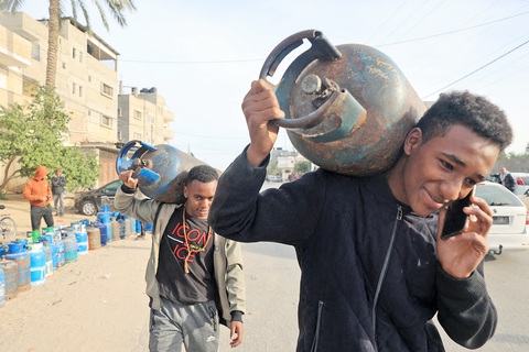 Gaza im tiếng súng và nước mắt đoàn tụ- Ảnh 1. Người dân ở phía nam Dải Gaza đem bình gas rỗng đón đoàn xe chở hàng cứu trợ, nhiên liệu và khí đốtquốc tế ngày 25-11 - Ảnh: AFP