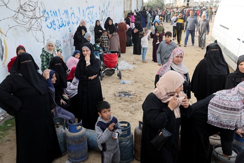 Số phụ nữ, trẻ em chết ở Gaza chưa từng có tiền lệ là do Israel dùng bom Mỹ?- Ảnh 1. Phụ nữ và trẻ em Palestine ở Dải Gaza xếp hàng để nhận gas và một số nhu yếu phẩm - Ảnh: REUTERS