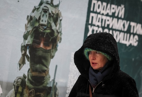 Một người phụ nữ đi ngang qua tấm áp phích quảng cáo có hình một quân nhân Ukraine trong trận tuyết rơi ở Kiev, Ukraine ngày 27-11 - Ảnh: REUTERS Một người phụ nữ đi ngang qua tấm áp phích quảng cáo có hình một quân nhân Ukraine trong trận tuyết rơi ở Kiev, Ukraine ngày 27-11 - Ảnh: REUTERS