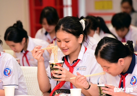 Học sinh tham quan nhà máy, viết trải nghiệm bằng tiếng Anh- Ảnh 4. Em Phương Lan (học sinh lớp 7A2, Trường THCS Đồng Khởi, quận 1, TP.HCM) thích thú thưởng thức mì - Ảnh: DUYÊN PHAN
