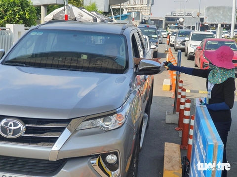 Phí ô tô vào sân bay: Bao giờ thu tự động?- Ảnh 1. Có nhiều thời điểm kẹt xe, nhân viên trạm thu phí ở sân bay Tân Sơn Nhất xông ra làn xe để thu tay, thay vì qua trạm barie như thông thường. Đây là hình ảnh thường thấy ở sân bay khi ô tô ùn tắc ở trạm thu phí - Ảnh: CÔNG TRUNG