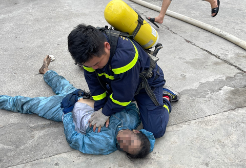 Cứu 4 người trong khu xưởng cháy ngùn ngụt- Ảnh 2. Cảnh sát sơ cứu cho một nạn nhân tại hiện trường - Ảnh: Công an cung cấp