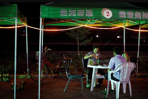 Đặc khu kinh tế Triều Tiên sôi động trở lại nhờ tăng cường giao lưu với Nga- Ảnh 1. Hỉnh ảnh người dân Triều Tiên uống bia tại một khu chợ ở đặc khu kinh tế Rason vào năm 2011 - Ảnh: REUTERS