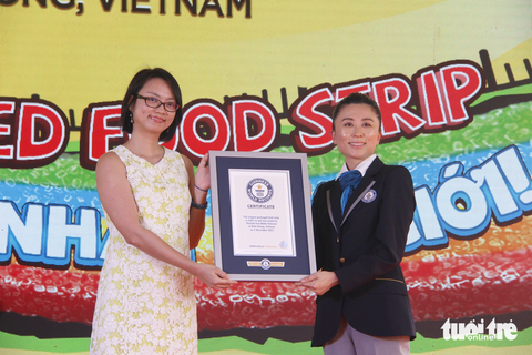 Dây kẹo dài nhất thế giới được tặng cho trẻ mái ấm- Ảnh 2. Bà Emi Saito - giám khảo chính thức của Tổ chức Guinness thế giới (phải) - trao chứng nhận xác lập kỷ lục dây kẹo dài nhất thế giới cho đại diện công ty - Ảnh: CÔNG TRIỆU
