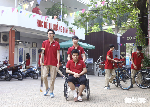 Nỗ lực trở lại lớp học của nam sinh nhảy từ tầng 9 thoát đám cháy chung cư - Ảnh 1. Nam sinh Trần Đại Phong đi xe lăn đến trường, được bạn bè hỗ trợ đưa vào lớp học - Ảnh: DANH TRỌNG