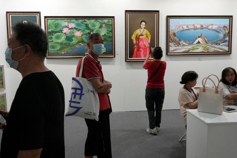 Những bức tranh vẽ về Triều Tiên giá cả ngàn đô được bán ở Trung Quốc - Ảnh 1. Khách tham quan triển lãm nghệ thuật Bắc Kinh hồi tháng 9 đi ngang qua một gian trưng bày các bức tranh vẽ về Triều Tiên của phòng trưng bày The Paintings Say Arirang - Ảnh: YONHAP/AP