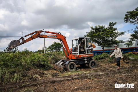 Gara, nhà xưởng mọc chui trên đất công, xã nói cho doanh nghiệp mượn - Ảnh 3. Xe múc đang triển khai san gạt mặt bằng khu đất công trên đường Đinh Văn Chất, xã Hòa Phước, để làm bãi xe - Ảnh: TẤN LỰC
