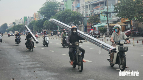 Xe ba gác, 'cà tàng' chở sắt thép... vẫn tung hoành ở TP.HCM - Ảnh 1. Hai người đi trên hai xe máy chở nhiều thanh kim loại dài ngoằng trên đường Tên Lửa (quận Bình Tân), chiều 7-11. Hai người này phải chạy một tay vì tay còn lại phải giữ thanh kim loại - Ảnh: NGỌC KHẢI