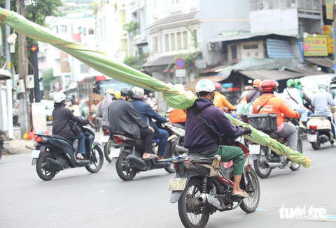 Xe ba gác, 'cà tàng' chở sắt thép... vẫn tung hoành ở TP.HCM - Ảnh 4. Nam thanh niên chạy xe máy bằng một tay, tay còn lại giữ một vật dài đang vác trên vai, chạy trên đường Ngô Gia Tự, quận 5 - Ảnh: MINH HÒA