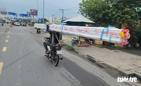 Xe ba gác, 'cà tàng' chở sắt thép... vẫn tung hoành ở TP.HCM - Ảnh 7. Nam thanh niên chở các thanh nhôm dài ngoằng, cồng kềnh trên xe máy ở đường An Dương Vương (quận Bình Tân) - Ảnh: NGỌC KHẢI