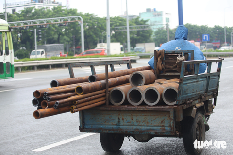 Xe ba gác, 'cà tàng' chở sắt thép... vẫn tung hoành ở TP.HCM - Ảnh 9. Xe ba gác chở nhiều thanh sắt tròn khá cồng kềnh, nhô ra phía sau, chạy trên quốc lộ 1 (quận Bình Tân) - Ảnh: MINH HÒA