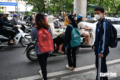 Nhiều người đi bộ bị CSGT xử phạt vì sang đường 'bất chấp' - Ảnh 2. Một nhóm sinh viên cắt ngang dòng phương tiện trên đường Xuân Thủy để đi bộ sang đường - Ảnh: HỒNG QUANG