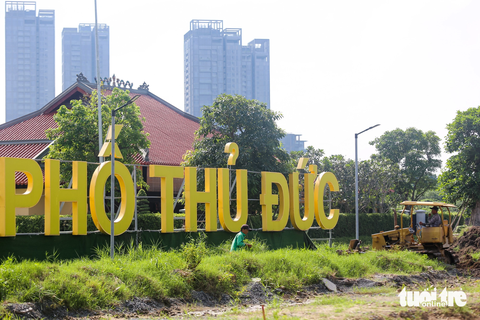 Lau sậy nhường chỗ, hoa hướng dương sắp nở ở bờ sông Sài Gòn phía Thủ Thiêm - Ảnh 6. Các công nhân đang dọn dẹp cỏ dại, san lấp phần trũng đọng nước trước đình thần An Khánh. Đề xuất cải tạo bờ sông Sài Gòn phía bên bờ Thủ Thiêm từ UBND TP Thủ Đức đang được dư luận rất quan tâm.