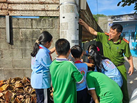 Củ Chi quyết liệt chấm dứt quảng cáo rao vặt trên cột điện, trụ đèn...- Ảnh 2. Công an địa phương hướng dẫn học sinh gỡ các tờ rơi quảng cáo - Ảnh: CTV
