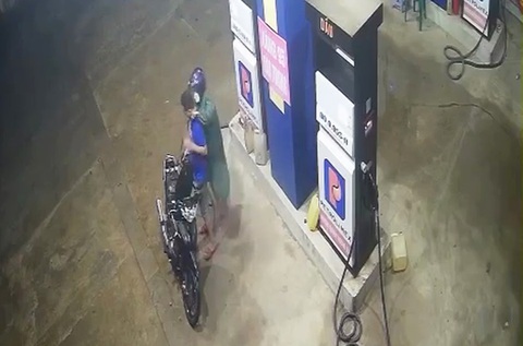 Truy nã đặc biệt nghi phạm cầm liềm kề cổ chủ cây xăng cướp tiền- Ảnh 1. Nghi phạm mặc áo mưa màu xanh, cầm liềm kề cổ chủ cây xăng ép đưa tiền - Ảnh: Camera an ninh
