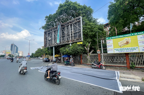 Bảng quảng cáo ‘trơ xương’, hiểm họa trên đầu người đi đường- Ảnh 9. Theo nhiều người dân, việc thường xuyên kiểm tra độ bền của bảng và bạt quảng cáo là hết sức cần thiết. Đồng thời, cơ quan có thẩm quyền cũng cần xử lý nghiêm và công khai các đơn vị quảng cáo trái phép hoặc không đảm bảo an toàn. Trong ảnh là một bảng quảng cáo tại vòng xoay Điện Biên Phủ đang được thay bạt mới - Ảnh: CHÂU TUẤN