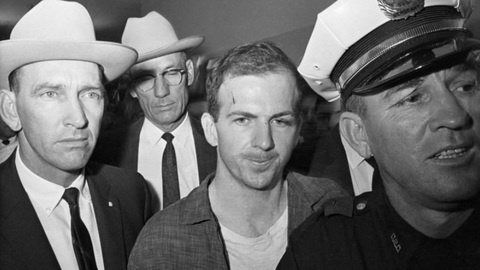 Phần Lan giải mật hồ sơ người ám sát Tổng thống Mỹ John F. Kennedy- Ảnh 1. Lee Harvey Oswald (ở giữa, không đội mũ) bị bắt ở Dallas, bang Texas sau khi ám sát Tổng thống Mỹ John F. Kennedy vào ngày 22-11-1963 - Ảnh chụp màn hình RT/GETTY IMAGES