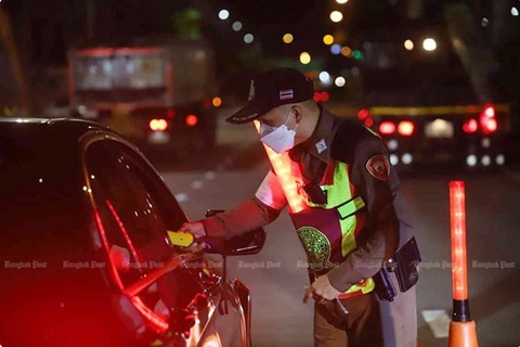 Thái Lan quy định quán nhậu xuyên đêm phải ngăn khách say rượu lái xe- Ảnh 1. Một cảnh sát kiểm tra nồng độ cồn của tài xế bằng máy đo hơi thở tại trạm kiểm soát ven đường tháng trước - Ảnh: Nutthawat Wichieanbut