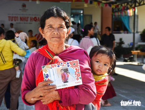 Bà Cà Chơm (xã Giang Ly) địu cháu trên lưng đến điểm chụp ảnh chân dung - Ảnh: TRẦN HOÀI Bà Cà Chơm (xã Giang Ly) địu cháu trên lưng đến điểm chụp ảnh chân dung - Ảnh: TRẦN HOÀI