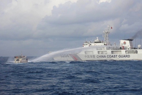 Philippines tìm cách mở dự án thăm dò dầu khí mới ở Biển Đông- Ảnh 1. Tàu cảnh sát biển Trung Quốc (phải) phun vòi rồng vào một tàu tiếp tế của Philippines ở vùng tranh chấp tại Bãi Cỏ Mây ngày 10-12 - Ảnh: AFP