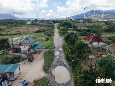 Đường sá vỡ vụn sau 2 năm thi công điện gió, thành ao cho vịt tắm- Ảnh 1. Nhiều hố nước sâu và rộng giữa đường, đằng sau là cánh đồng điện gió rộng lớn - Ảnh: HOÀNG TÁO