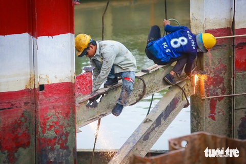 Tháo dỡ cầu sắt Rạch Đỉa nối quận 7, Nhà Bè để làm cầu mới- Ảnh 5. Các công nhân đang cắt các thanh sắt của trụ chống va đập của cầu cũ - Ảnh: CHÂU TUẤN