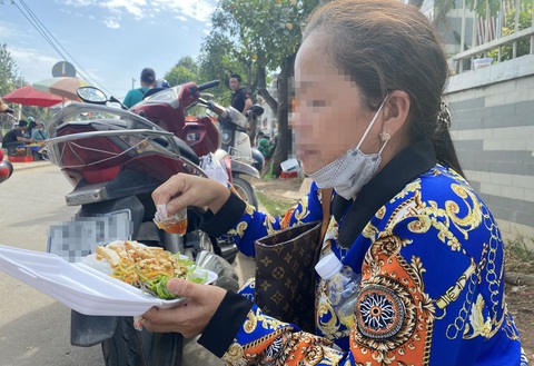 Bệnh nhân ung thư và suất ăn từ thiện: Đắn đo giá trị dinh dưỡng và tiết kiệm tiền chữa bệnh- Ảnh 4. Trong thời gian chờ kết quả tái khám, chị T. (mắc ung thư tuyến giáp giai đoạn 1, đã mổ) ngồi trên vỉa hè trước Bệnh viện Ung bướu TP.HCM ăn tạm một hộp bún xào gồm đậu hũ chiên, rau, hạt đậu phộng... - Ảnh: XUÂN MAI