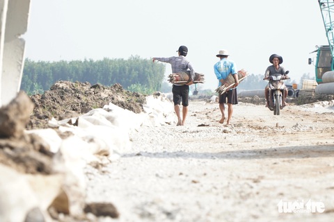 Thiếu cát, phải mót từng xe, đắp từng mét đường ở công trường cao tốc trục ngang dài nhất miền Tây- Ảnh 2. Thiếu cát, đường công vụ ngổn ngang, người dân thong dong đi giăng câu, chăn vịt - Ảnh: CHÍ HẠNH
