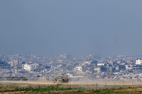 Hamas nã rocket vào Israel, còi báo động vang lên ở Tel Aviv- Ảnh 1. Ảnh chụp từ miền nam Israel cho thấy một chiếc xe quân sự của Israel di chuyển gần các tòa nhà bị hư hại ở Dải Gaza vào ngày 19-12 - Ảnh: REUTERS