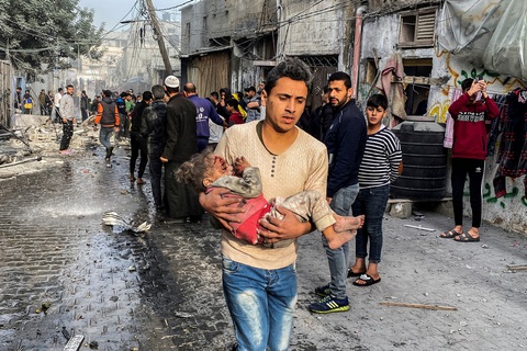 Israel tấn công trở lại, người Palestine chết và bị thương cả ngàn- Ảnh 1. Một người Palestine bế em bé bị thương từ cuộc không kích của Israel ở thành phố Rafah, phía nam Dải Gaza - Ảnh: REUTERS